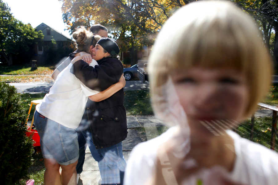 Beth Mackie, left, hugs friend Carol Bachelor as Mackie's daughter Lily, 3, stands in the doorway of the Mackie home on moving day in Wheaton, Ill. The family was forced to leave their home after it fell into foreclosure.  : Moments : Madison | Milwaukee | Chicago | Writer | Photographer | Keri Wiginton | Portrait photography | Travel | Corporate | Photojournalist | Editorial | Environmental